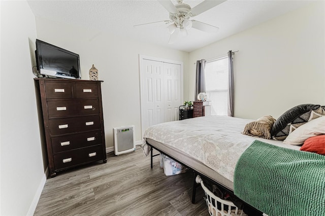 bedroom with a ceiling fan, a textured ceiling, wood finished floors, a closet, and baseboards