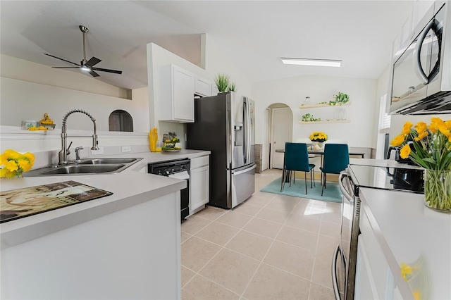 kitchen with vaulted ceiling, arched walkways, white cabinets, stainless steel appliances, and a sink