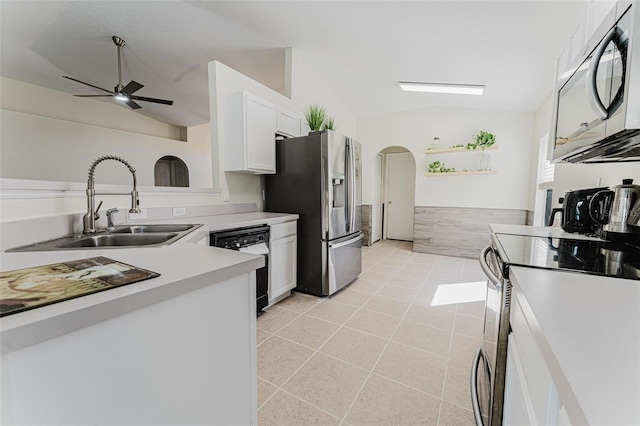 kitchen with arched walkways, a sink, stainless steel appliances, vaulted ceiling, and white cabinetry