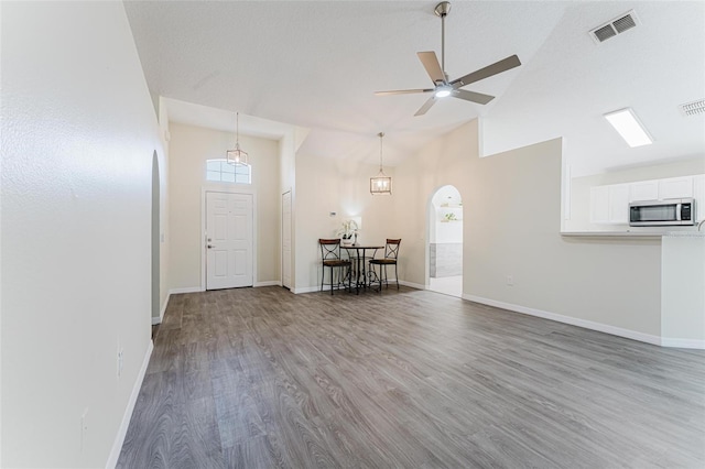 entrance foyer with visible vents, arched walkways, baseboards, and wood finished floors