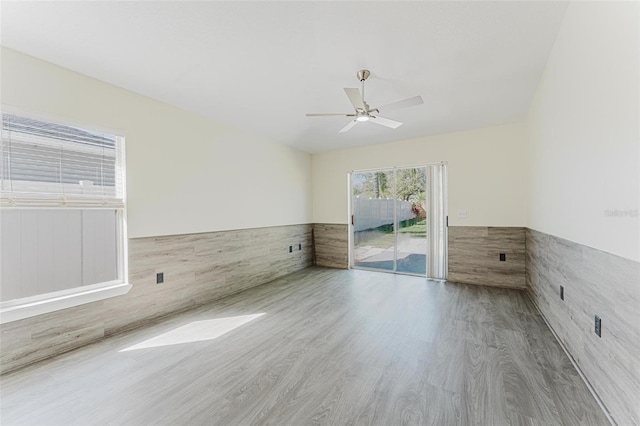 spare room featuring a ceiling fan, wood finished floors, and a wainscoted wall