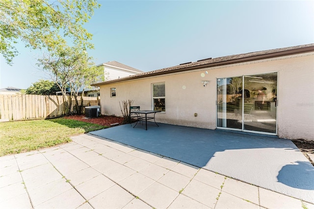 back of property with fence, stucco siding, cooling unit, a yard, and a patio