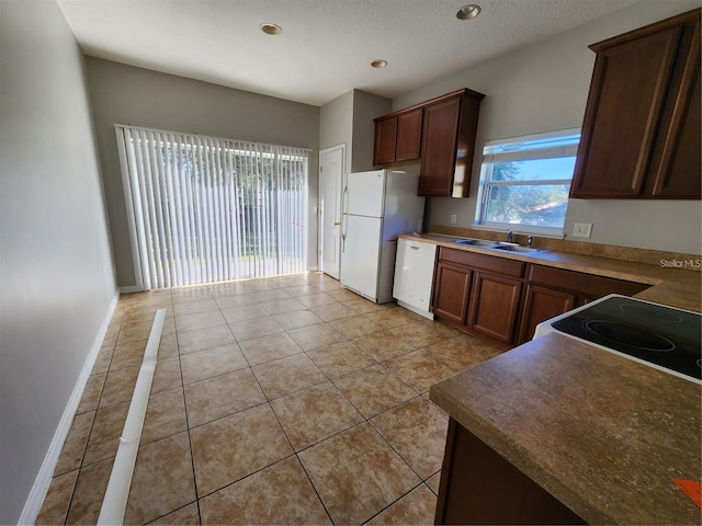 kitchen featuring baseboards, light tile patterned floors, recessed lighting, white appliances, and a sink