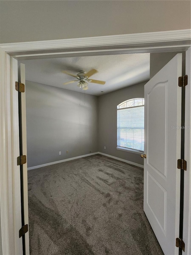 spare room featuring carpet flooring, baseboards, and ceiling fan