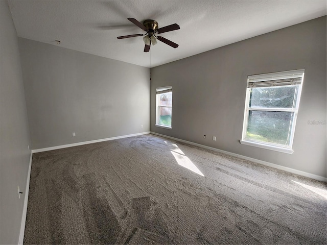 carpeted spare room with a textured ceiling, baseboards, and ceiling fan