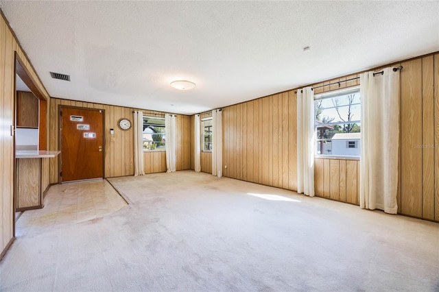 interior space featuring visible vents, light colored carpet, and multiple windows