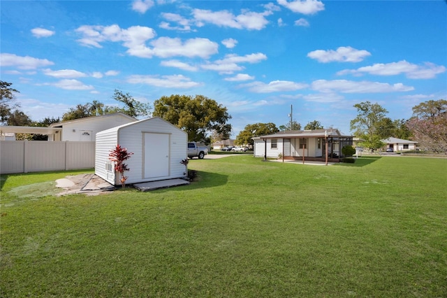 view of yard featuring a storage unit, an outbuilding, and fence