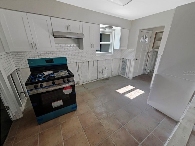 kitchen featuring light countertops, white cabinets, under cabinet range hood, stainless steel gas range oven, and backsplash