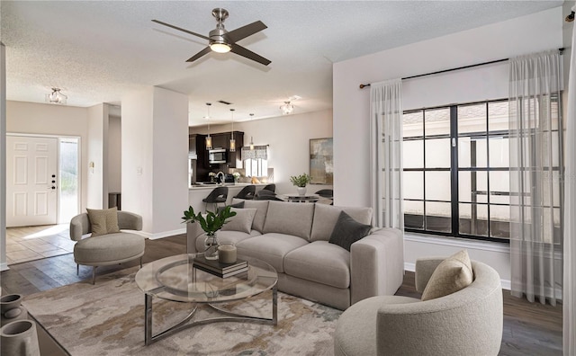 living area with a wealth of natural light, a textured ceiling, a ceiling fan, and wood finished floors