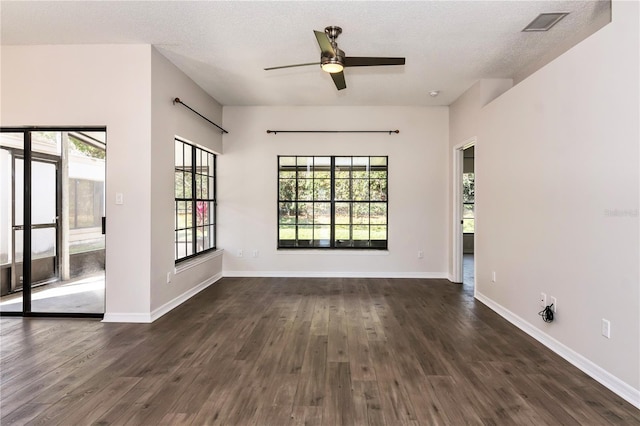 spare room featuring visible vents, a healthy amount of sunlight, dark wood finished floors, and a ceiling fan