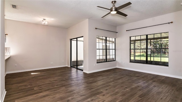 empty room featuring visible vents, baseboards, dark wood finished floors, ceiling fan, and a textured ceiling