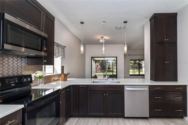 kitchen with tasteful backsplash, dark brown cabinets, light countertops, appliances with stainless steel finishes, and a sink