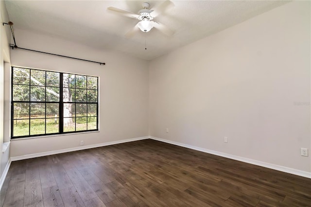 unfurnished room featuring baseboards, dark wood finished floors, and a ceiling fan