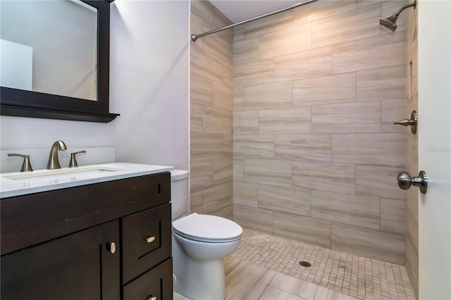 bathroom with vanity, toilet, and tiled shower