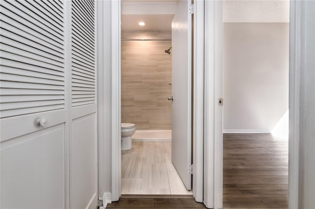 full bathroom featuring a shower stall, toilet, wood finished floors, and a textured ceiling