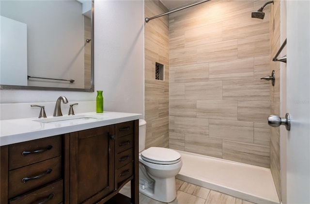 full bath with vanity, toilet, and a tile shower