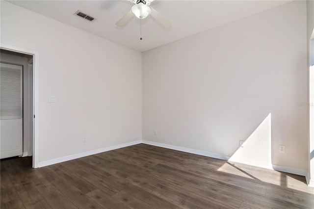 empty room featuring visible vents, baseboards, a ceiling fan, and dark wood-style flooring