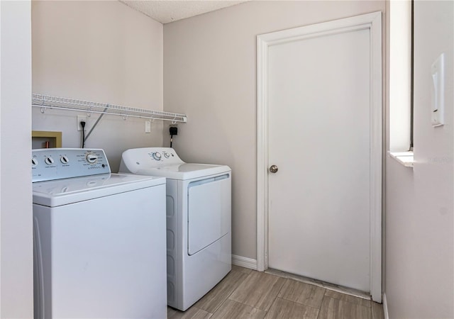 washroom with wood finish floors, baseboards, laundry area, and washer and clothes dryer