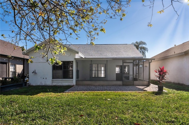 back of property with roof with shingles, a yard, a sunroom, and stucco siding