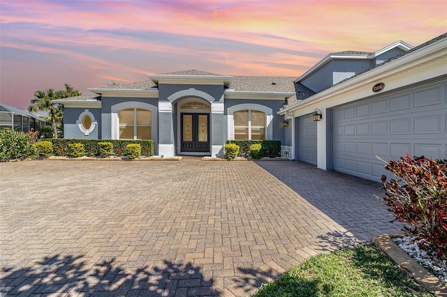 mediterranean / spanish-style house with decorative driveway, french doors, a garage, and stucco siding