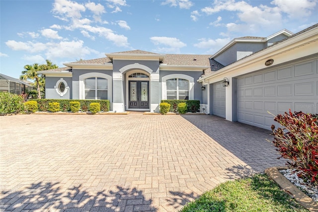 mediterranean / spanish-style home featuring stucco siding, french doors, decorative driveway, and a garage