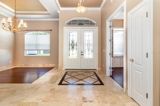 foyer featuring crown molding, baseboards, a tray ceiling, and a chandelier