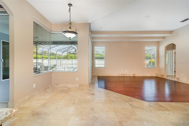 empty room with arched walkways, visible vents, and baseboards