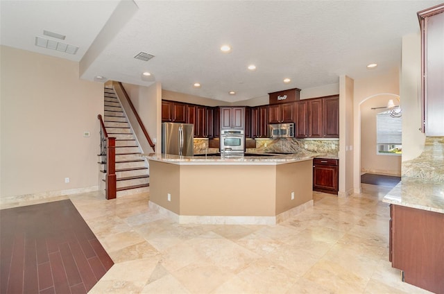 kitchen with tasteful backsplash, an island with sink, visible vents, and stainless steel appliances