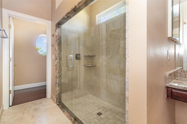 bathroom featuring baseboards, a stall shower, and vanity