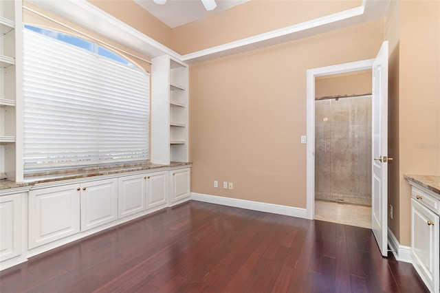 unfurnished room featuring baseboards, dark wood-style flooring, and ceiling fan