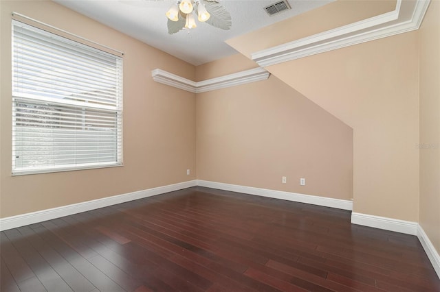 spare room with dark wood-style floors, visible vents, a ceiling fan, and baseboards