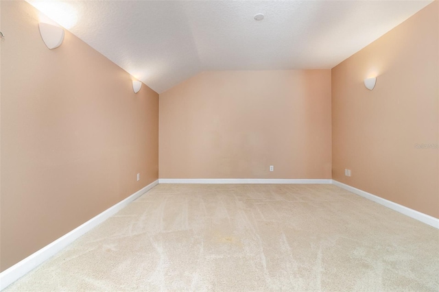 bonus room with lofted ceiling, light colored carpet, baseboards, and a textured ceiling