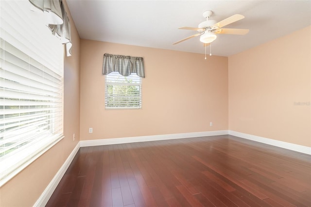 spare room featuring a ceiling fan, dark wood-style floors, and baseboards