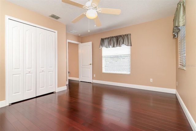 unfurnished bedroom featuring a closet, visible vents, baseboards, and wood finished floors