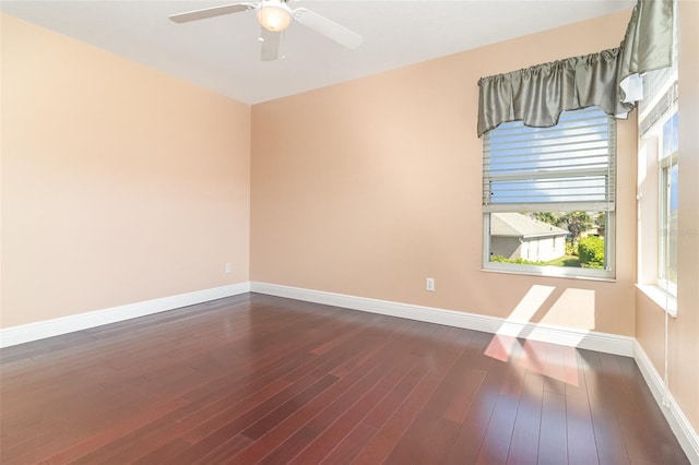 spare room with a ceiling fan, dark wood-style floors, and baseboards