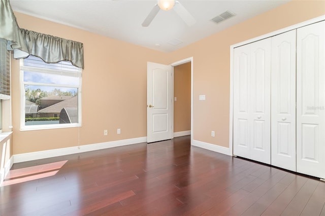 unfurnished bedroom featuring visible vents, wood finished floors, a closet, baseboards, and ceiling fan