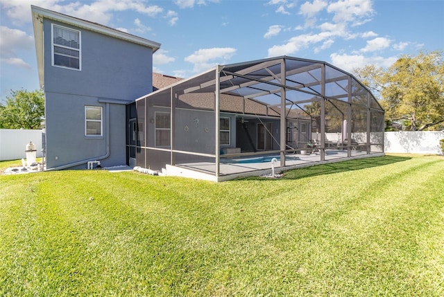 back of house with a yard, stucco siding, a lanai, and a fenced backyard