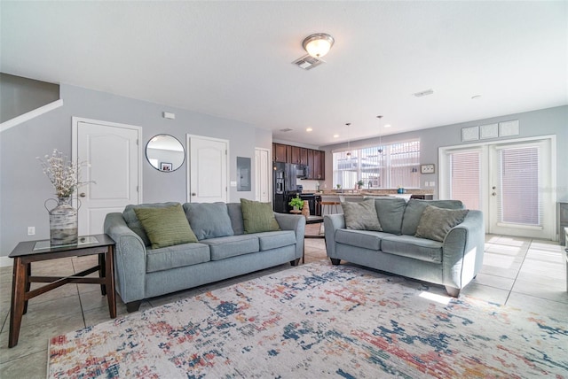 living room featuring light tile patterned flooring, visible vents, recessed lighting, and electric panel