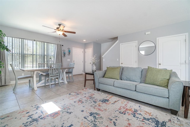 living area featuring light tile patterned floors, baseboards, and ceiling fan