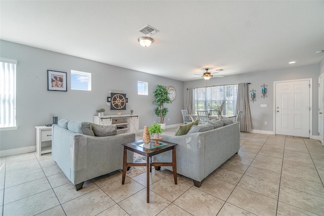 living area with light tile patterned floors, visible vents, baseboards, and ceiling fan