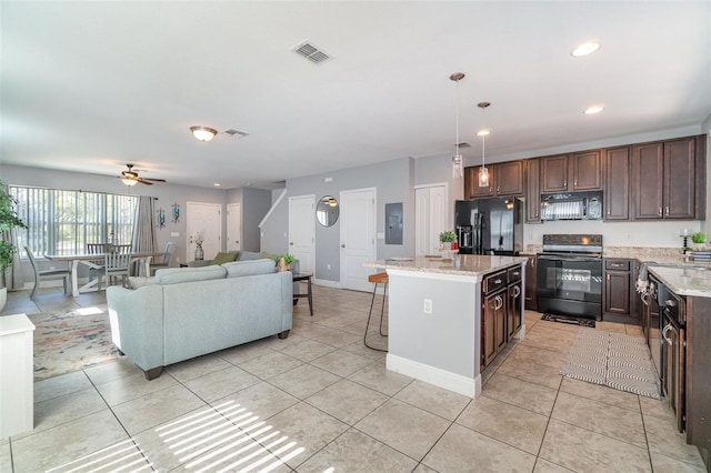 kitchen with visible vents, black appliances, a kitchen breakfast bar, a center island, and light tile patterned flooring