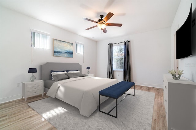 bedroom with light wood-style flooring, baseboards, and ceiling fan