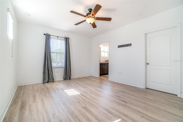 spare room featuring baseboards, light wood-type flooring, and ceiling fan