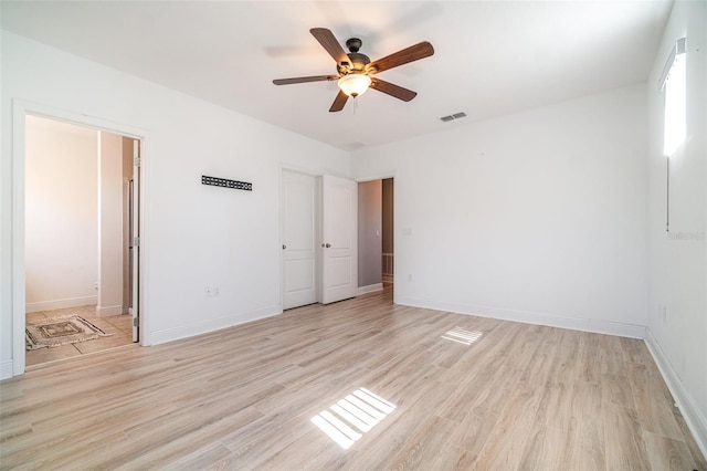 empty room with ceiling fan, visible vents, baseboards, and light wood-style flooring