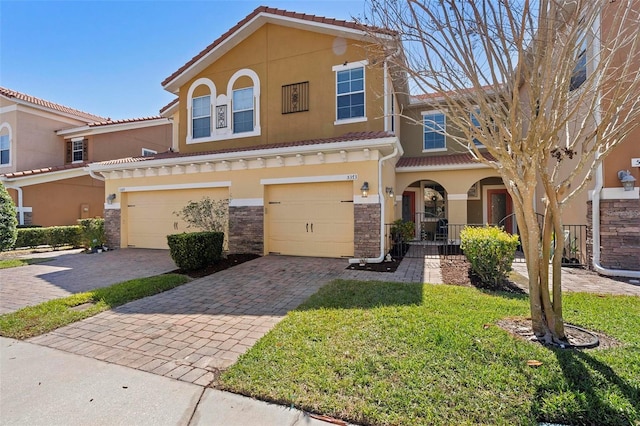 view of front facade featuring a tiled roof, decorative driveway, a garage, and stucco siding