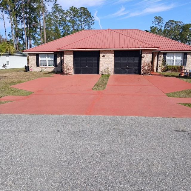 ranch-style house featuring a garage, brick siding, metal roof, and concrete driveway