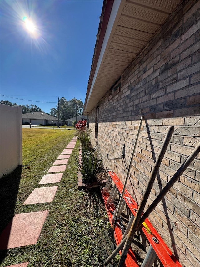 view of side of home featuring brick siding and a lawn