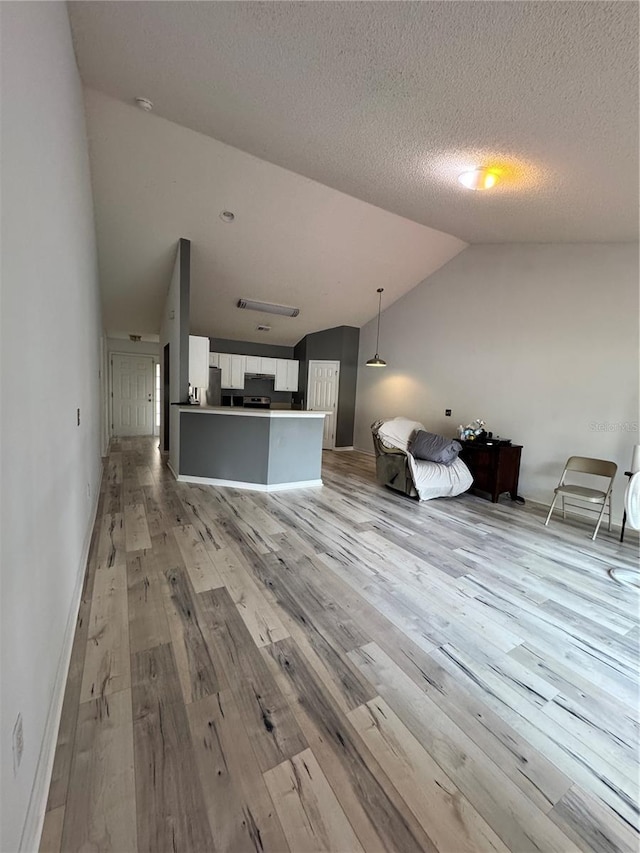 unfurnished living room featuring a textured ceiling, light wood-style floors, and lofted ceiling