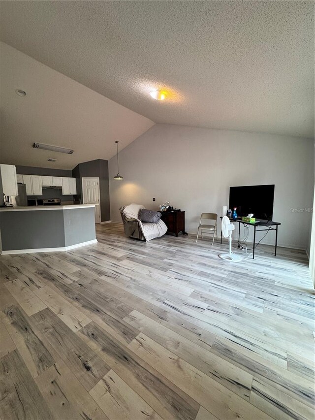 unfurnished living room featuring light wood finished floors, a textured ceiling, and vaulted ceiling