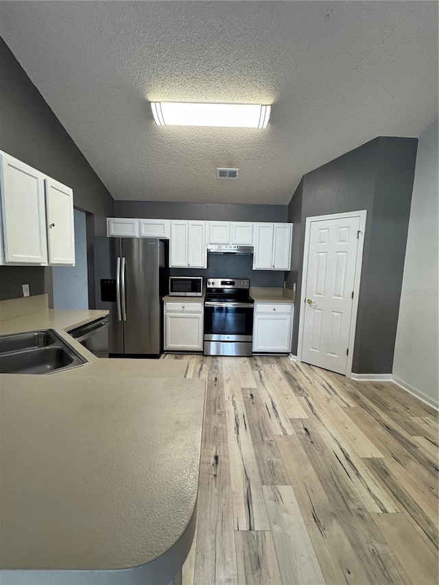 kitchen with light wood-type flooring, visible vents, white cabinetry, stainless steel appliances, and lofted ceiling